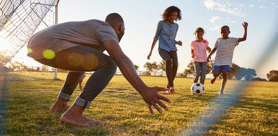 A boy kicks a football during a game with his family